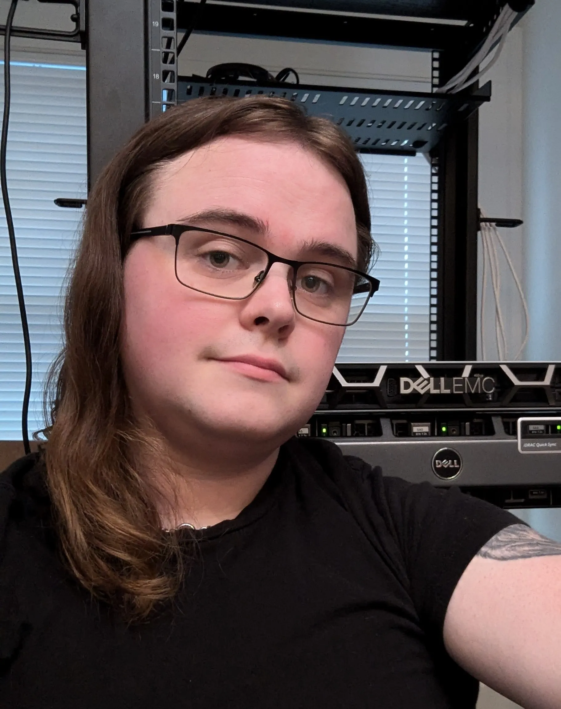 Zoe in front of a server rack in her homelab